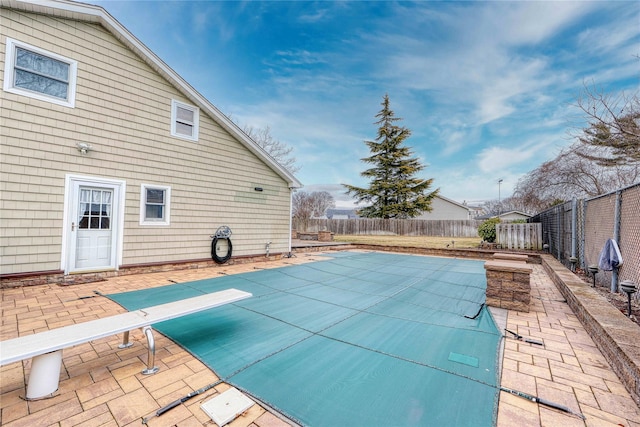 view of pool with a diving board and a patio