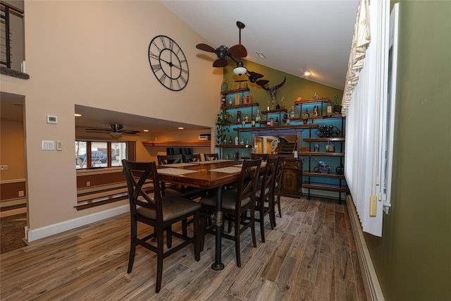 dining area with hardwood / wood-style flooring, ceiling fan, and high vaulted ceiling