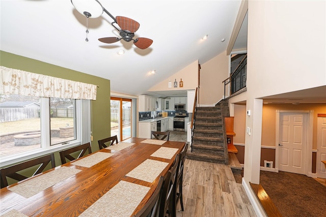 dining area featuring ceiling fan, high vaulted ceiling, and light wood-type flooring