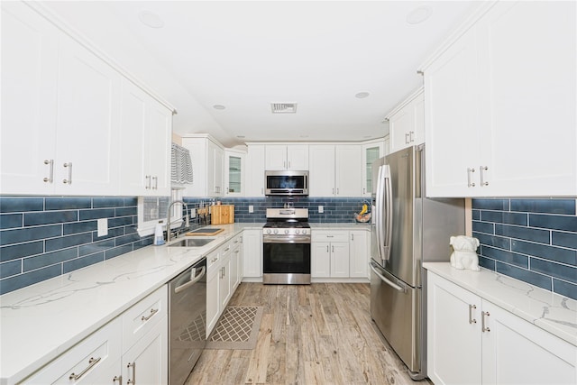 kitchen with light stone counters, sink, white cabinets, and appliances with stainless steel finishes