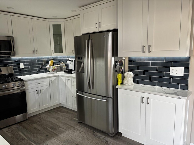 kitchen with white cabinetry, light stone counters, dark hardwood / wood-style flooring, and stainless steel appliances