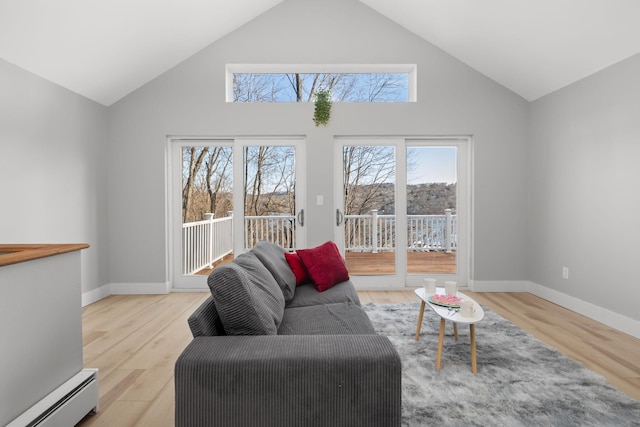 living room with high vaulted ceiling, a baseboard heating unit, and light hardwood / wood-style floors