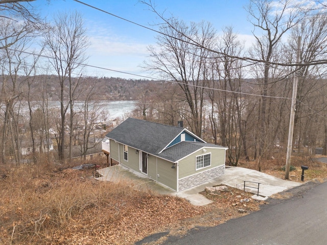 view of side of property featuring roof with shingles, a chimney, and stone siding