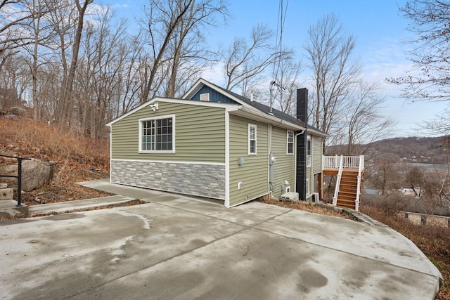 view of side of home featuring a chimney, stairs, and a deck
