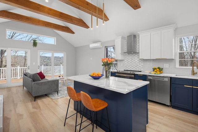 kitchen featuring wall chimney range hood, beamed ceiling, a sink, stainless steel appliances, and light wood-type flooring