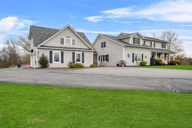 traditional-style house featuring a shingled roof and a front lawn