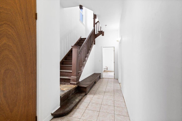 stairs featuring tile patterned flooring, a towering ceiling, and baseboards