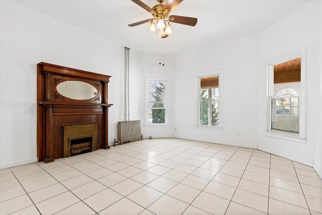 unfurnished living room with plenty of natural light, light tile patterned floors, radiator heating unit, and a fireplace