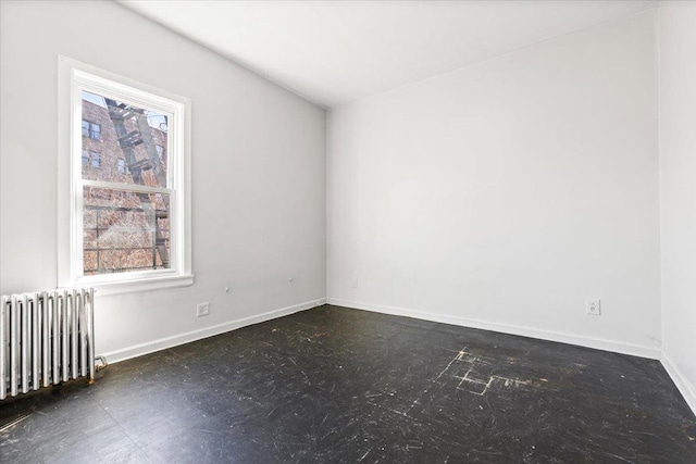 spare room with radiator heating unit, a wealth of natural light, and baseboards