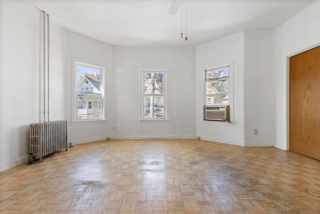 spare room with baseboards, ceiling fan, cooling unit, and radiator