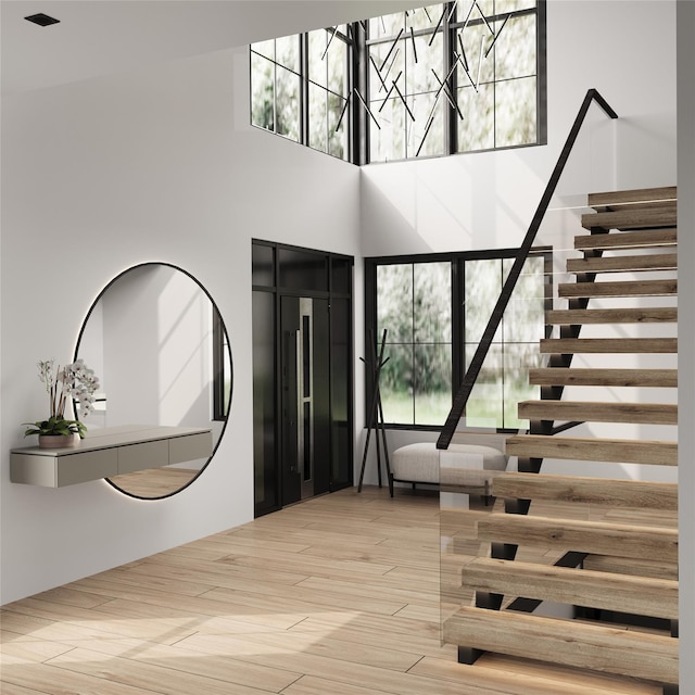 entryway with a towering ceiling and light wood-type flooring