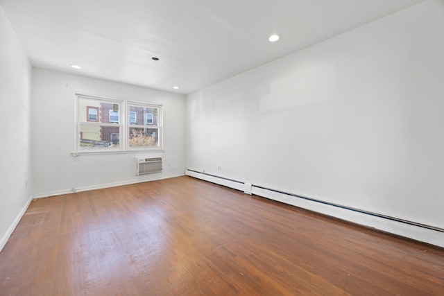 unfurnished room with a baseboard heating unit, a wall mounted air conditioner, and wood-type flooring