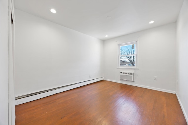 spare room featuring wood-type flooring, a baseboard radiator, and a wall mounted AC