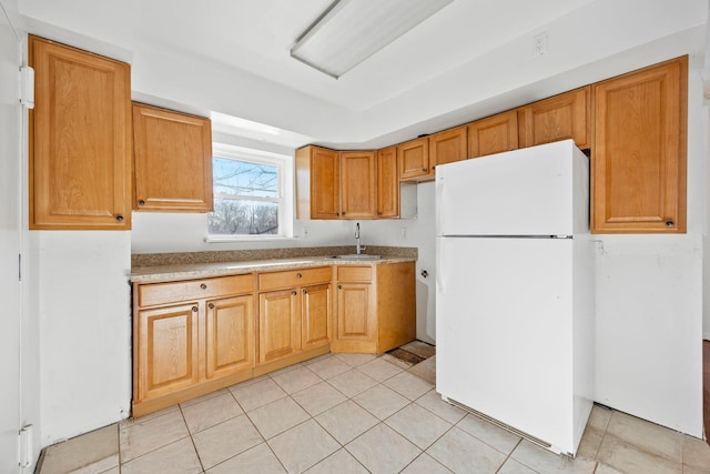 kitchen with white refrigerator, sink, and light tile patterned floors