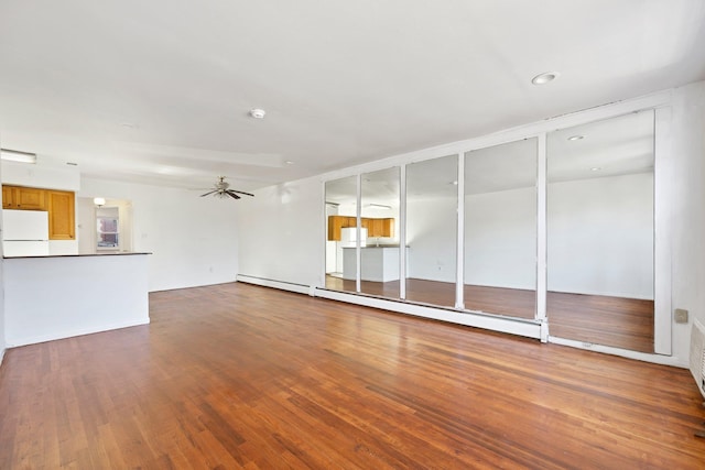 unfurnished living room featuring ceiling fan, wood-type flooring, and a baseboard heating unit