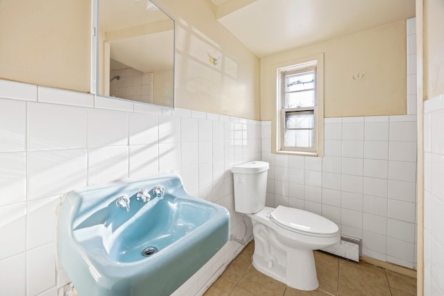 bathroom with sink, baseboard heating, tile walls, tile patterned floors, and toilet