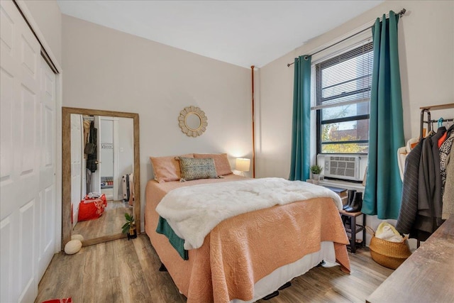 bedroom with cooling unit, wood-type flooring, lofted ceiling, and a closet