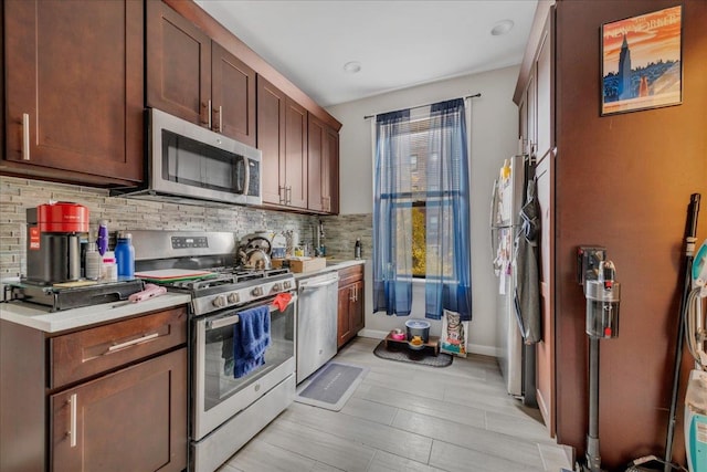 kitchen with appliances with stainless steel finishes, light hardwood / wood-style floors, and backsplash