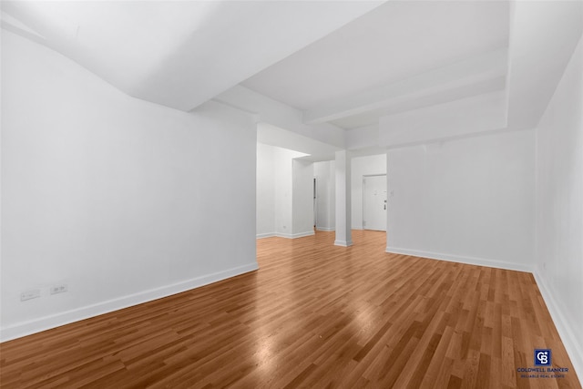 empty room with hardwood / wood-style floors and beam ceiling