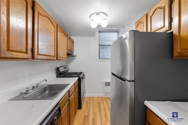 kitchen with sink, light hardwood / wood-style flooring, stainless steel refrigerator, radiator, and range with gas stovetop