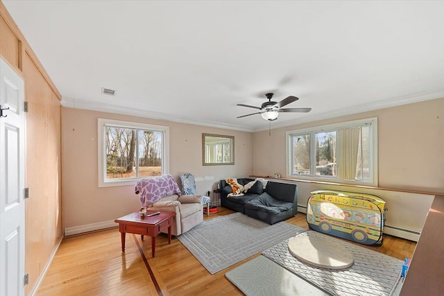 living area featuring ornamental molding, baseboard heating, and light hardwood / wood-style flooring