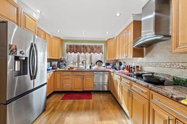 kitchen featuring wall chimney range hood, light hardwood / wood-style flooring, stone counters, appliances with stainless steel finishes, and backsplash