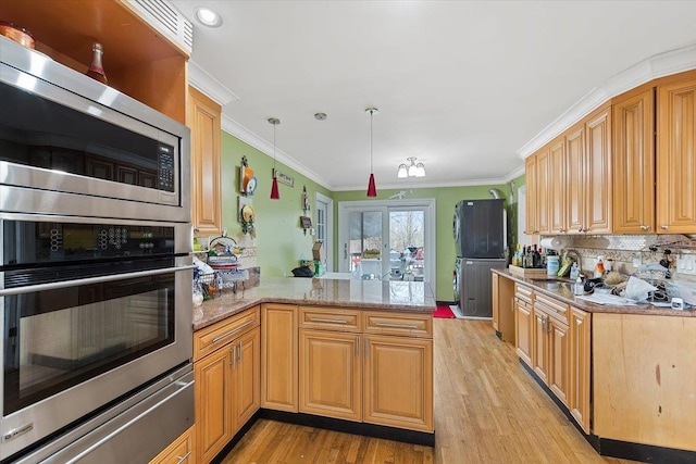 kitchen with crown molding, light hardwood / wood-style flooring, stainless steel microwave, kitchen peninsula, and pendant lighting