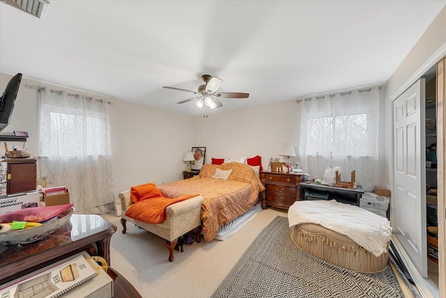 carpeted bedroom with ceiling fan, a closet, and multiple windows