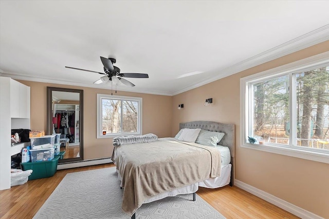 bedroom with ornamental molding, light hardwood / wood-style floors, a closet, and baseboard heating