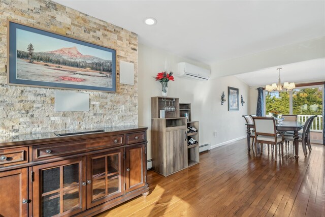 dining area featuring a notable chandelier, hardwood / wood-style floors, a wall unit AC, and a baseboard heating unit