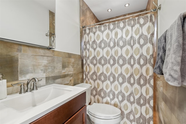 bathroom with tile walls, vanity, toilet, and a shower with shower curtain