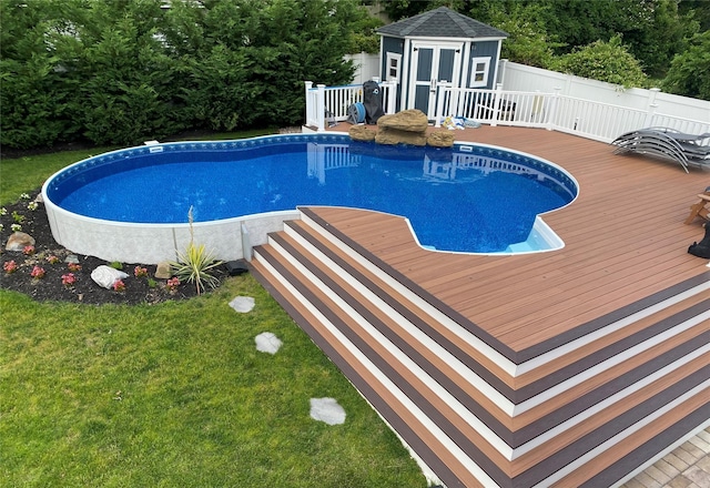 view of swimming pool with a wooden deck and a storage unit