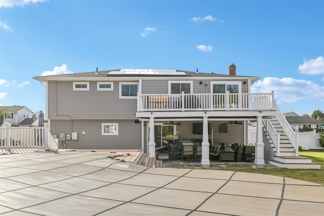 rear view of property with a patio, a deck, and solar panels