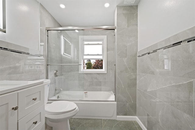 full bathroom featuring tile walls, vanity, toilet, and combined bath / shower with glass door