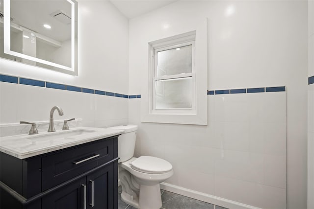 bathroom with tile patterned flooring, vanity, tile walls, and toilet