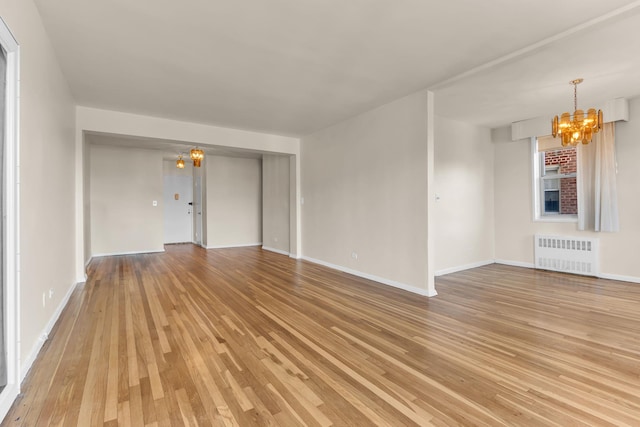 unfurnished living room featuring light hardwood / wood-style flooring, a notable chandelier, and radiator heating unit