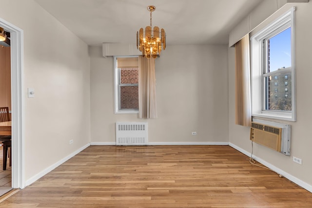 unfurnished dining area with radiator, a wall mounted air conditioner, an inviting chandelier, and light hardwood / wood-style flooring