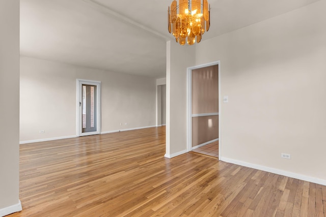 empty room featuring light hardwood / wood-style flooring and a chandelier