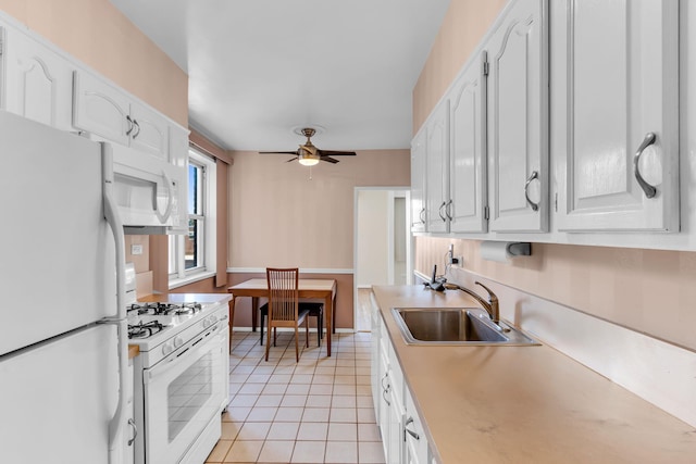 kitchen with sink, white appliances, light tile patterned floors, ceiling fan, and white cabinets