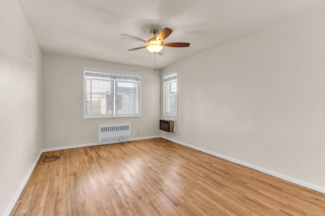 spare room with heating unit, ceiling fan, radiator heating unit, and light hardwood / wood-style flooring