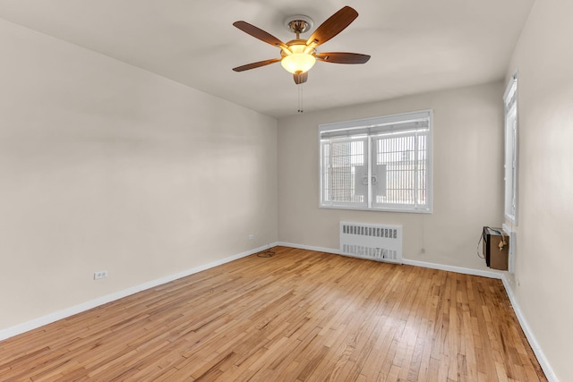 empty room with radiator heating unit, ceiling fan, and light wood-type flooring