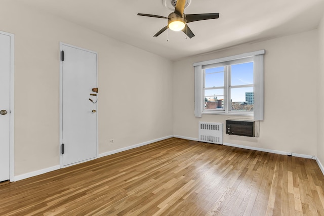 unfurnished living room featuring ceiling fan, radiator heating unit, a wall mounted AC, and light hardwood / wood-style flooring