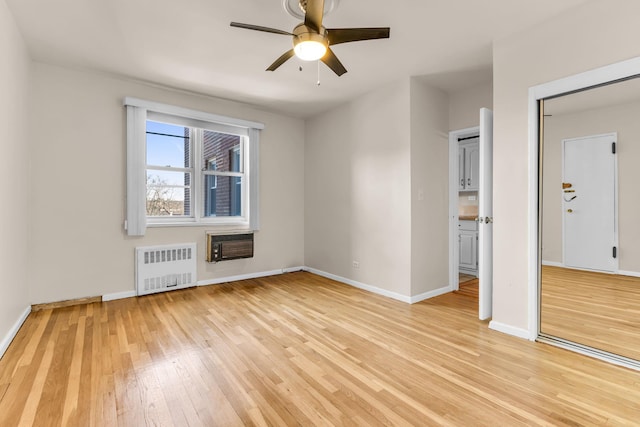 empty room with radiator heating unit, light hardwood / wood-style floors, and ceiling fan