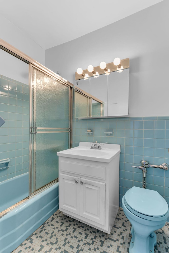 full bathroom with enclosed tub / shower combo, tile walls, vanity, tile patterned floors, and toilet