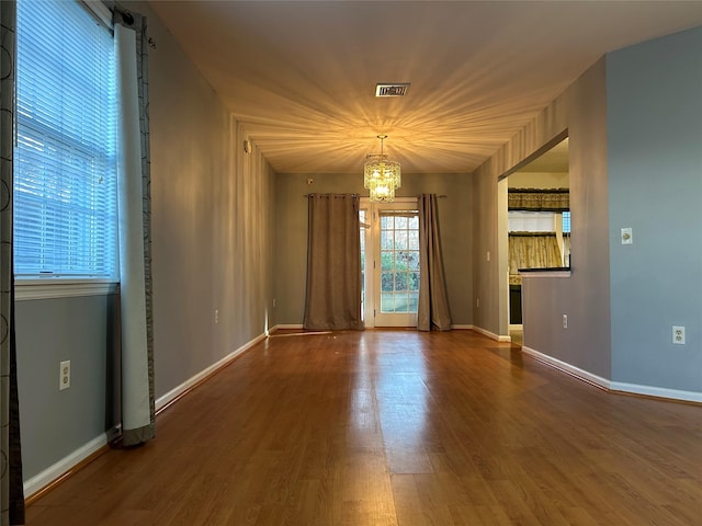 empty room featuring an inviting chandelier, hardwood / wood-style floors, and a barn door