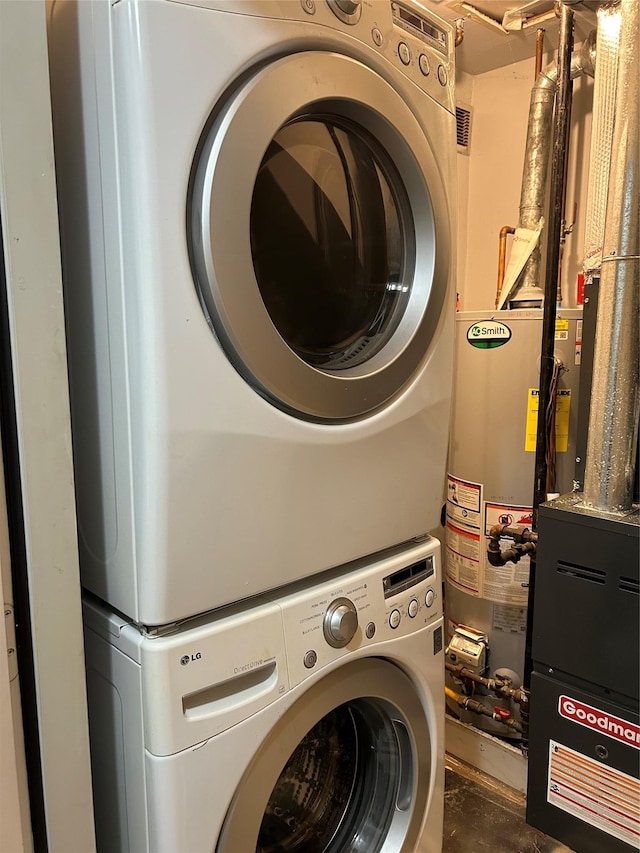 clothes washing area with water heater and stacked washer and clothes dryer