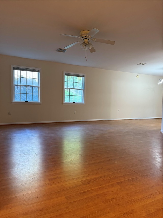 empty room featuring light wood-style flooring, a ceiling fan, and baseboards