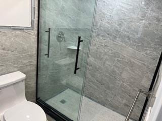 bathroom with tiled shower, tile walls, and toilet