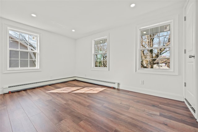 empty room with a wealth of natural light, baseboard heating, recessed lighting, and wood finished floors