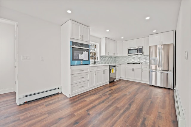 kitchen featuring stainless steel appliances, a baseboard heating unit, decorative backsplash, and white cabinetry